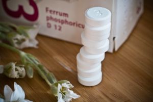 Impfreaktion auf die Coronaimpfung mit Schüßler-Salzen abmildern: zu sehen sind gestapelte Schüßler-Salz Tabletten, im Hintergrund ist die Verpackung zu sehen